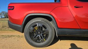 Close-up of Continental TerrainContact H/T tire on a Rivian R1T electric pickup truck, highlighting tread design and sidewall branding.