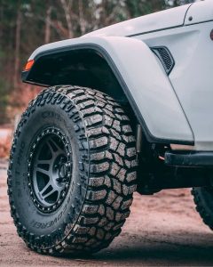 Cooper Discoverer STT Pro tire mounted on a Jeep, showing its aggressive tread design and deep sidewall lugs for extreme off-road traction.