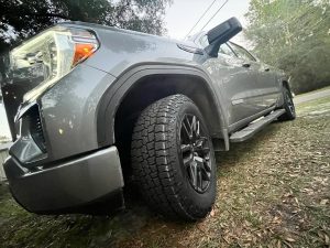 Close-up of Cooper Discoverer Road+Trail A/T tire mounted on a GMC Sierra, showing all-terrain tread designed for daily comfort and weekend adventures.