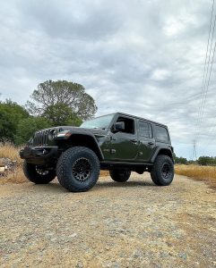 Jeep Wrangler Rubicon fitted with Nitto Recon Grappler A/T tires on black alloy wheels, showcasing aggressive tread design and lifted stance on a rocky trail.