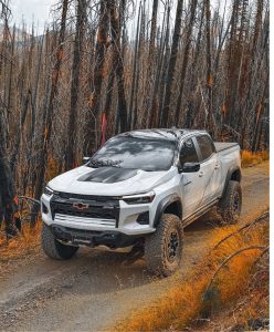 Chevy Colorado equipped with Toyo Open Country R/T Trail tires driving through a forest trail, showing aggressive tread and durable sidewalls for off-road traction.