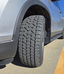 Close-up of Bridgestone Dueler A/T Ascent tire on an SUV, showing its balanced tread design for all-terrain grip, highway comfort, and 3PMSF-certified winter traction.