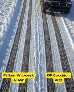 Side-by-side tire tracks in snow made by Falken Wildpeak AT4W (left) and BFGoodrich KO2 (right), with a Toyota Tacoma partially visible at the top of the frame.