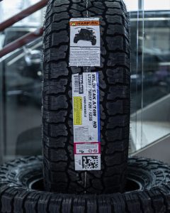 Close-up of a Falken Wildpeak AT4W HD tire with factory label showing LT285/70R17 size, Load Range E, and tread details for heavy-duty use.