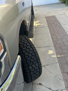 Cooper Discoverer Stronghold AT tire mounted on a truck, highlighting aggressive tread blocks and wide stance designed for dirt, mud, sand, and rocky trails.