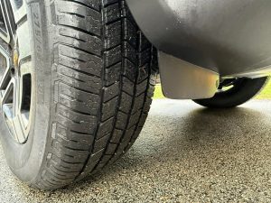 Close-up of Michelin Defender LTX M/S2 tire mounted on an SUV, showing detailed tread pattern designed for wet grip, quiet ride, and long tread life.