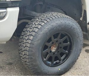 Close-up of Sumitomo Encounter AT2 tire mounted on a truck, showing its deep tread blocks and aggressive shoulder design for off-road traction.