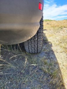 Cooper Discoverer Road+Trail AT tire navigating dry grassland and sandy soil in Wyoming backcountry during remote outdoor adventure.